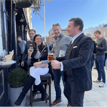 Group of people talking and smiling drinking beer outside